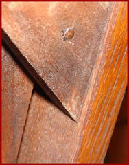 Nail head on one of the glue blocks under the seat, showing the nail head with a trace of paper label signature. 